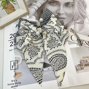 Macro view of vintage houndstooth satin bow hair clip with elegant pearl accents