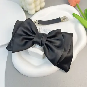 Close-up of elegant black satin bow hair clip on aesthetic white display plate