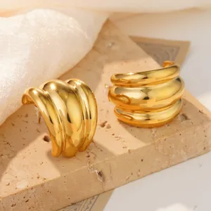 Macro detail of golden stainless steel conch stud earrings featuring ripple texture