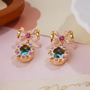 Detailed close-up of vintage enamel flower earrings with a pink bowknot and gem