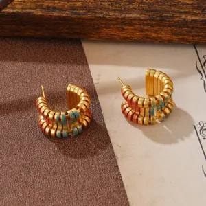 Detaillierte Nahaufnahme von goldenen Vintage-Creolen mit handbemalter bunter Emaille