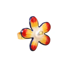 Detailed macro shot of a colorful enamel flower ring featuring a gold leaf pearl center