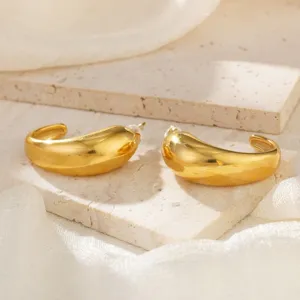Elegante Nahaufnahme von glatten goldenen Creolen auf einem Travertinblock platziert