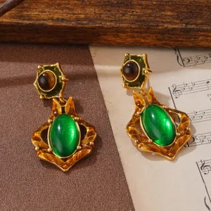Nahaufnahme von antiken Ohrringen im Palaststil mit grünen ovalen Edelsteinen in Gold