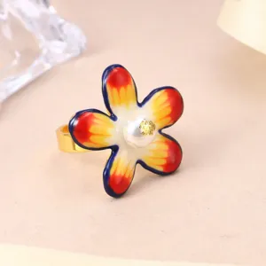 Macro view of an adjustable golden ring with a colorful enamel flower and central pearl