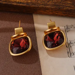 Detailansicht von goldenen Ohrringen im französischen Vintage-Stil mit roten Kristallen.