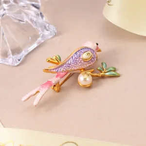 Exquisite close-up of a pink enamel bird brooch featuring a natural pearl on a golden branch