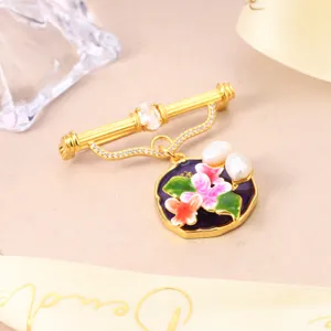 Macro detail of elegant gold-plated flower brooch with natural pearls and purple enamel.