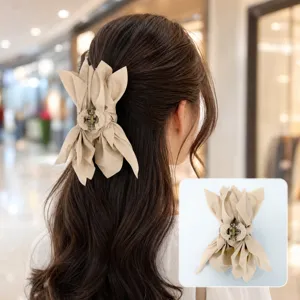 Close-up detail of a stylish beige fabric bow hair claw clip worn in wavy brown hair.