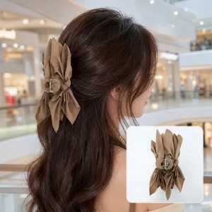 Large brown fabric bow hair claw clip worn on model's hair in a mall setting