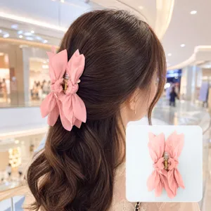 Close-up of elegant pink fabric bow claw clip worn in hair with product detail inset