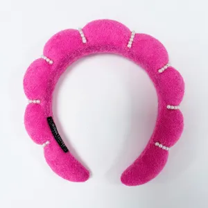 Primer plano de diadema acolchada rosa con perlas y etiqueta hecha a mano