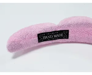 Detailed close-up of a pink sponge headband with a black Hand Made woven label.