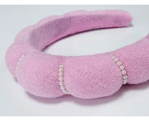 Primer plano de diadema nube rosa con perlas blancas y suave textura de toalla.