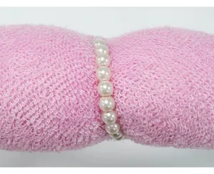 Vista detallada de una diadema de esponja rosa hecha a mano con elegantes perlas blancas.