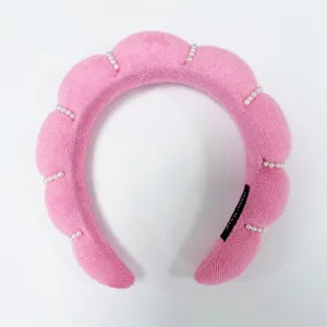 Primer plano de una diadema rosa acolchada con diseño de nube y detalles de perlas.