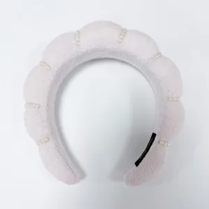 Vista macro detallada de una diadema acolchada rosa decorada con perlas blancas a mano.