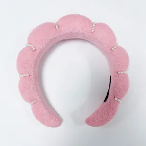 Detalle de una diadema de nube de esponja rosa con elegantes adornos de perlas blancas