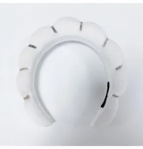 Close-up detail of white cloud sponge headband with elegant rhinestone bar embellishments