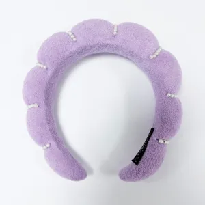 Vista macro detallada de acentos de perlas blancas en diadema de nube morada texturizada