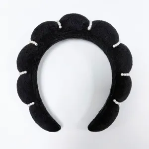 Detalle de diadema de esponja negra en forma de nube con adornos de perlas blancas elegantes.