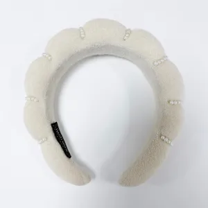 Vista detallada de una diadema acolchada color crema con elegantes perlas de imitación