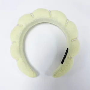 Vista detallada de una diadema de nube de esponja amarillo claro con detalles de perlas blancas