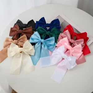 Assorted sweet candy colored ribbon bow hair clips displayed on a white table surface.