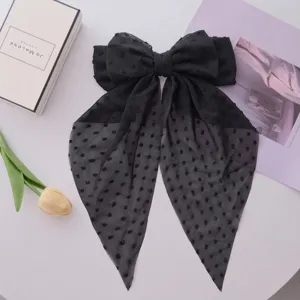 Detail view of a black chiffon polka dot bow hair clip featuring elegant flowing ribbons
