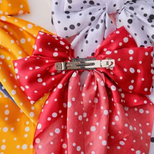 Close-up of the metal clip mechanism on a large satin polka dot bow hair accessory