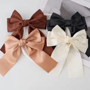 Close-up detail of four elegant satin ribbon bow hair clips in chic earth tones