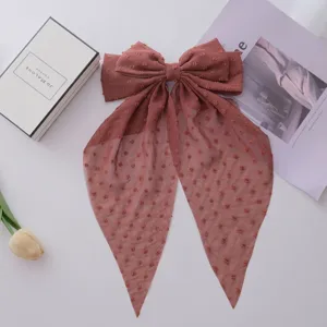 Close-up of terracotta chiffon bow hair clip with textured dots and long ribbons