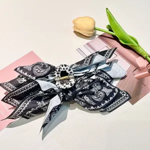 Detailed view of a large black and white paisley print fabric bow hair claw clip.