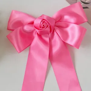 Macro detail of handmade pink satin ribbon bow hair clip featuring a center rose