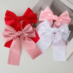 Detail view showing red, pink, and white satin ribbon bow hair clips for various stylings.