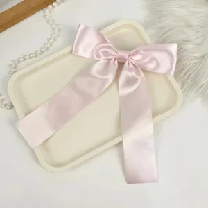 Exquisite macro detail of a soft pink satin bow hair clip with elegant long ribbons.
