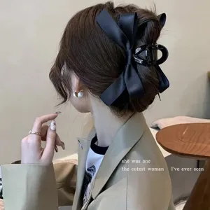 Close-up detail of an elegant black ribbon bow hair claw clip on a woman's hair bun.