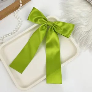 Close-up of lime green satin bow hair clip with long ribbon streamers for hair styling