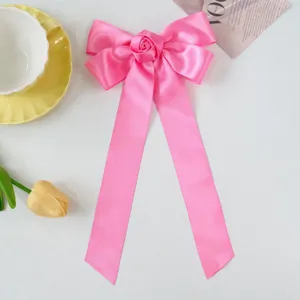 Macro view of pink ribbon bow hair clip with rose detail and long streamers