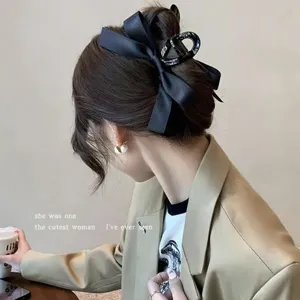 Detail of elegant Hepburn style black satin ribbon bow hair claw clip on bun