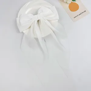 Close-up detail of an elegant white chiffon bow hair clip with long flowing ribbons