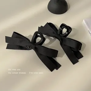 Detailed view of elegant black ribbon bow shark clips in matte and glossy finishes