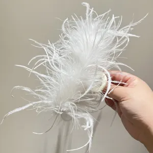 Detail of a large white ostrich feather hair claw clip held in hand against a neutral background