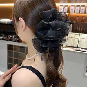 Elegant large black mesh flower hair claw clip with feather accents on a ponytail.