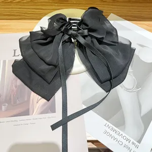 Detail view of a French style black textured chiffon bow hair claw clip for women