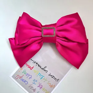 Close-up of hot pink satin bow hair clip featuring a gold-tone square chain link