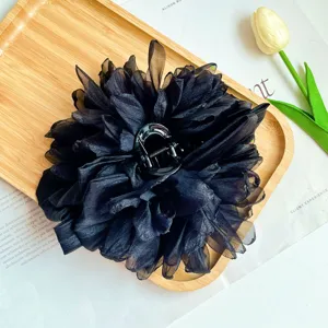 Dettaglio di un grande fermaglio per capelli a fiore in tessuto nero con petali fini