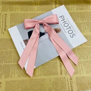 Detailed view of a large pink ribbon bow hair clip with elegant long streamers