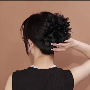 Gedetailleerd beeld van een elegante zwarte stoffen bloem haarklem met fijne verenaccenten
