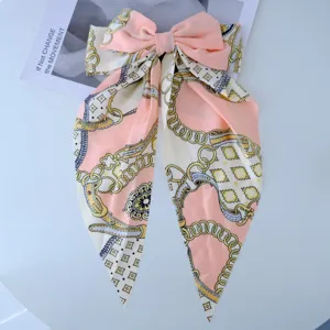 Large peach bow hair clip with elegant chain pattern streamers and silky texture